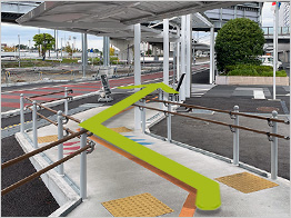 スロープを下り横断歩道を渡ります。緑色の歩行帯に沿ってお進みください。